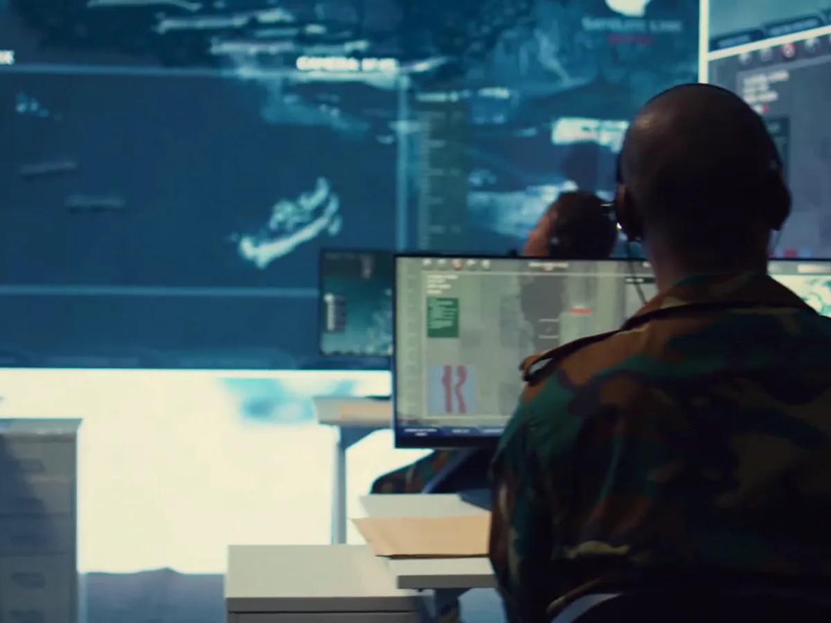Military personnel monitoring satellite reconnaissance feeds in an operations room