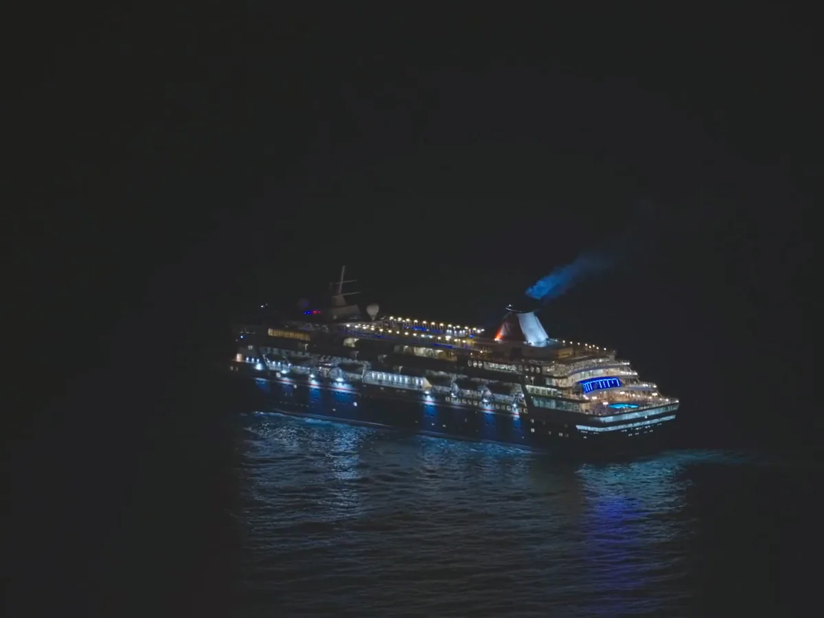 Aerial view of an illuminated ship under way on a dark ocean
